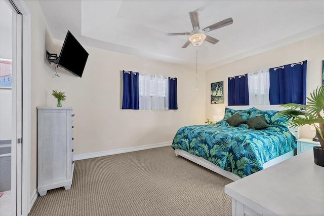 bedroom featuring ceiling fan, a raised ceiling, and carpet floors