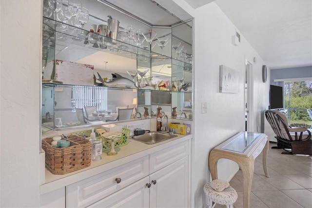 interior space featuring sink, light tile floors, and white cabinetry