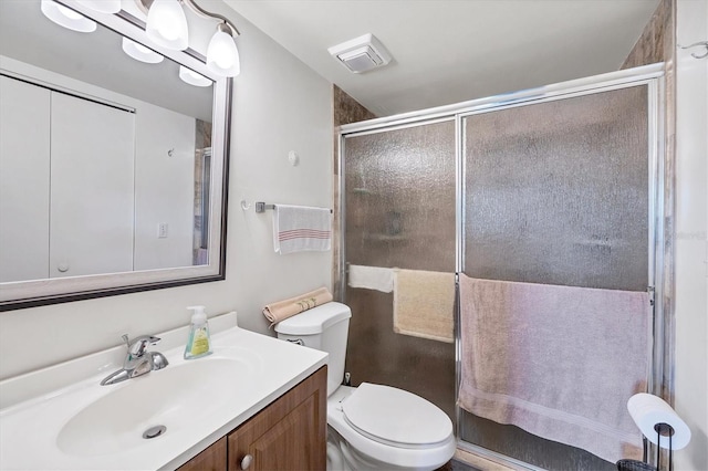 bathroom featuring vanity, toilet, and a shower with shower door