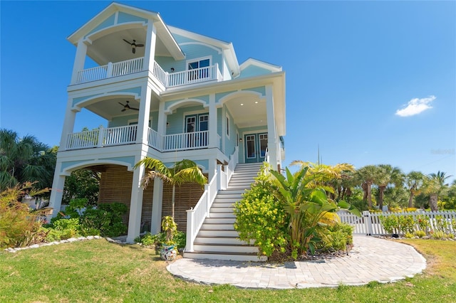 raised beach house featuring a front lawn, a balcony, ceiling fan, and a porch