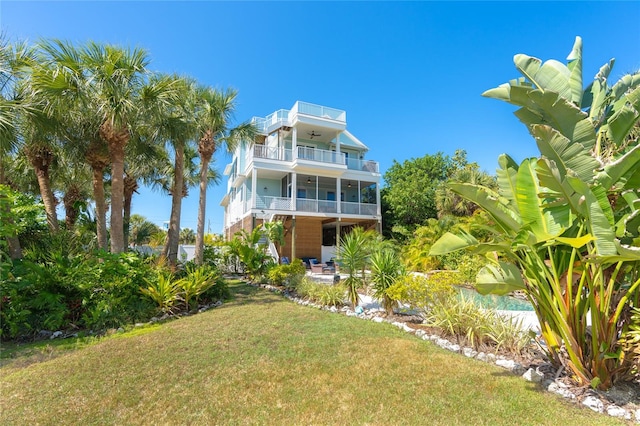 rear view of property featuring a balcony and a lawn