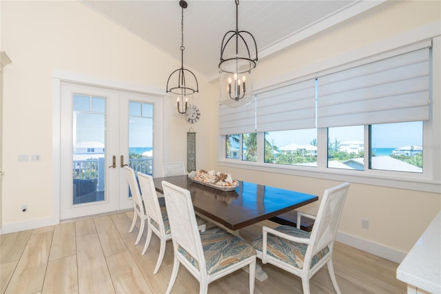 dining area featuring a water view, french doors, light hardwood / wood-style floors, and an inviting chandelier