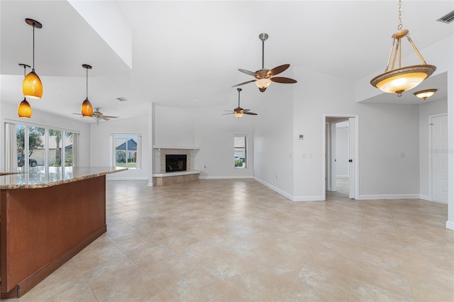 unfurnished living room with vaulted ceiling, ceiling fan, light tile flooring, and a tiled fireplace