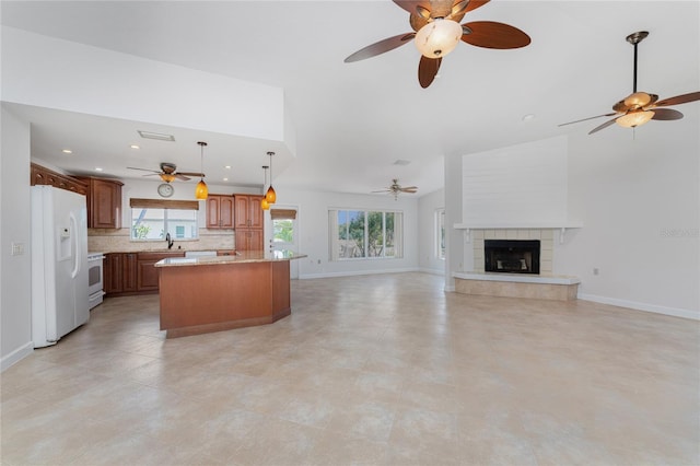 unfurnished living room featuring ceiling fan, a healthy amount of sunlight, a tile fireplace, and light tile floors