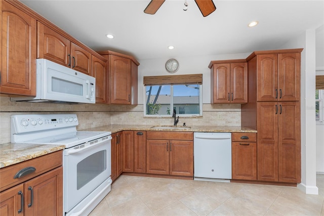 kitchen with a wealth of natural light, ceiling fan, white appliances, and light stone countertops