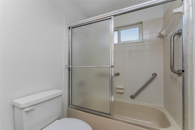 bathroom featuring toilet and combined bath / shower with glass door