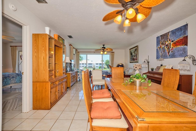 tiled dining area with ceiling fan and a textured ceiling