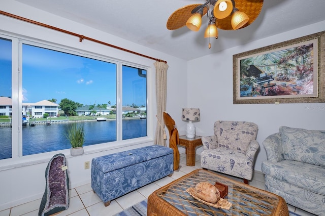 tiled living room featuring ceiling fan and a water view