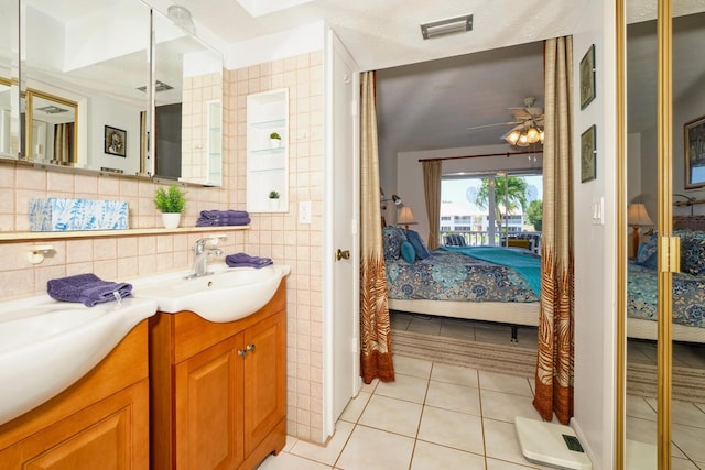 bathroom with vanity with extensive cabinet space, tile floors, tile walls, ceiling fan, and a textured ceiling