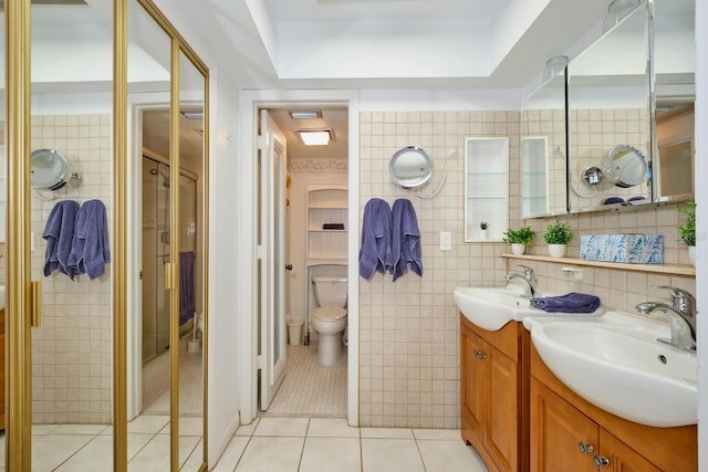 bathroom with tile walls, large vanity, toilet, tile flooring, and a tray ceiling