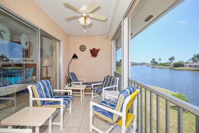 sunroom with ceiling fan and a water view