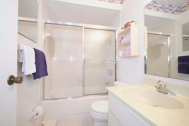 full bathroom featuring tile flooring, vanity, toilet, and bath / shower combo with glass door