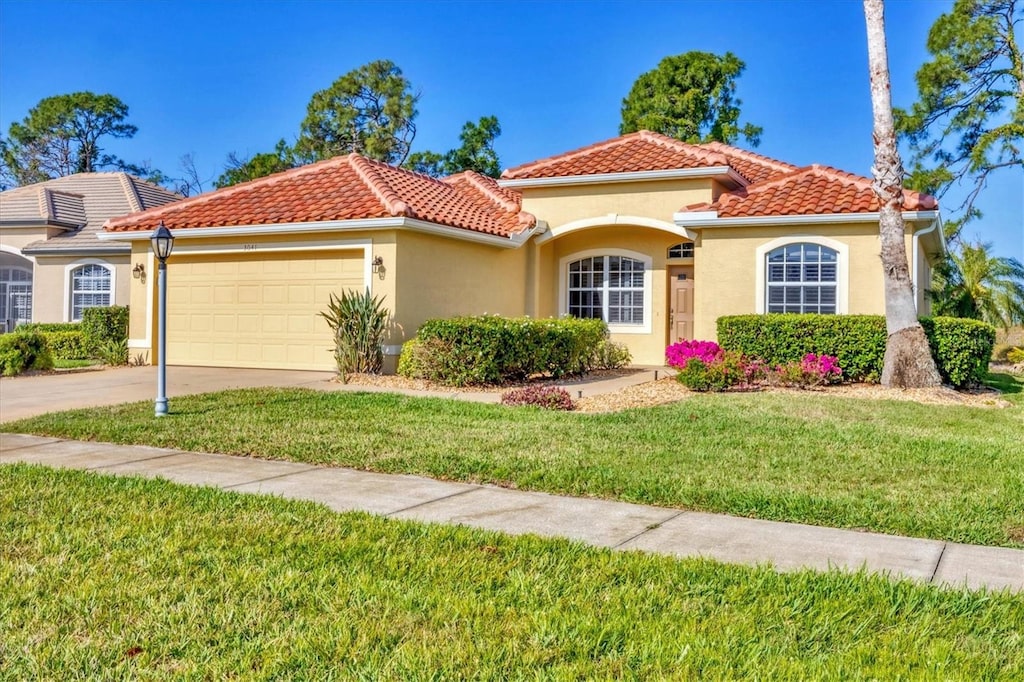 mediterranean / spanish-style home featuring a garage and a front lawn