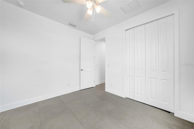 unfurnished bedroom with tile patterned floors, ceiling fan, and a closet