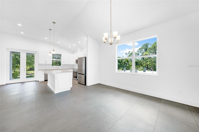 kitchen with vaulted ceiling, a kitchen island, stainless steel refrigerator, and decorative light fixtures