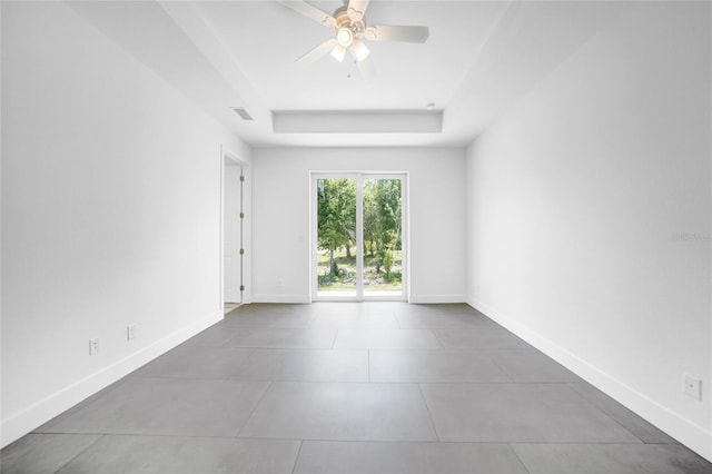 empty room featuring a raised ceiling and ceiling fan