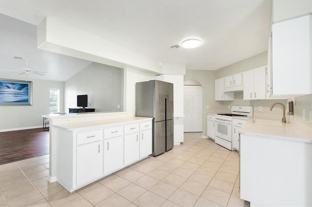 kitchen with stainless steel refrigerator, white gas range, ceiling fan, sink, and white cabinets