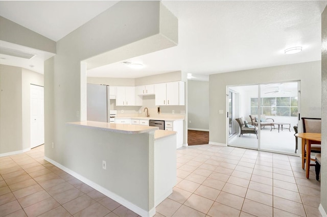 kitchen with dishwasher, light tile patterned floors, white cabinetry, and sink