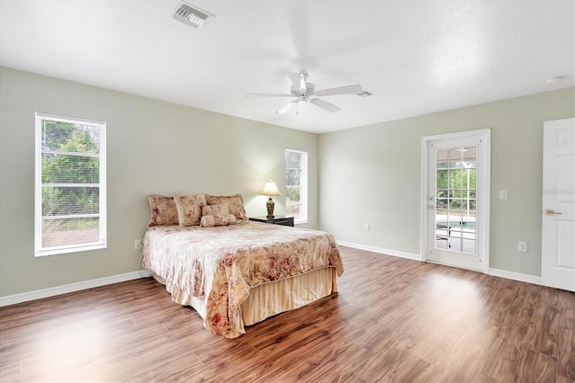 bedroom featuring ceiling fan, wood-type flooring, access to outside, and multiple windows