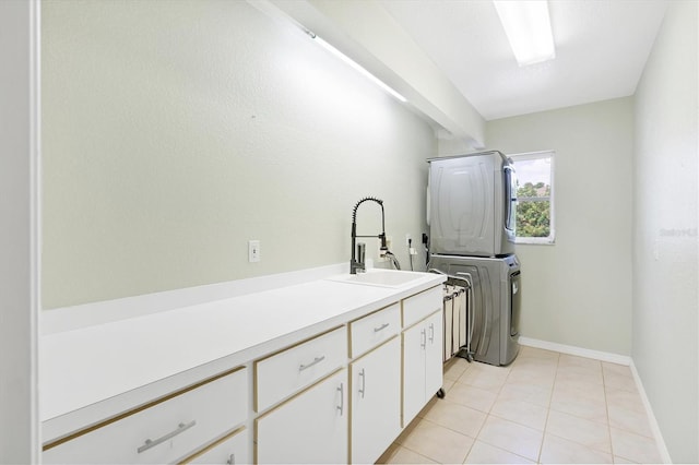 washroom featuring sink, light tile patterned flooring, cabinets, and stacked washer / drying machine