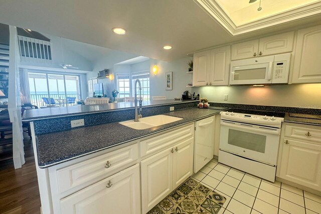 kitchen with light tile flooring, kitchen peninsula, white cabinets, sink, and white appliances