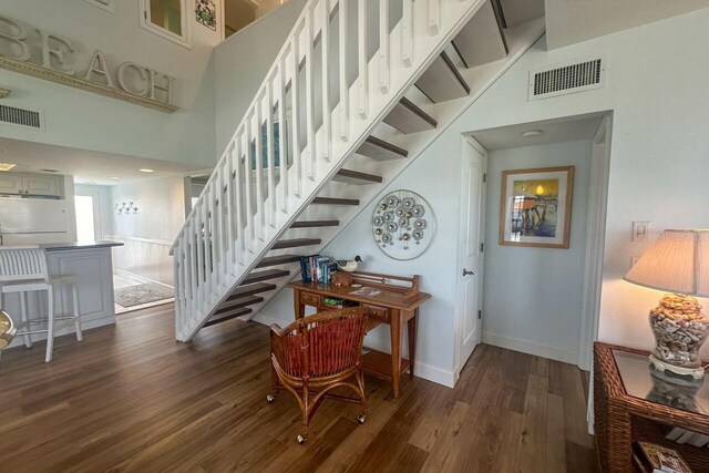 stairway with dark hardwood / wood-style flooring and a high ceiling