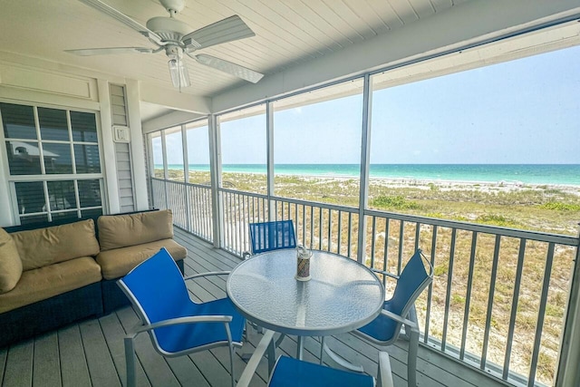 sunroom / solarium featuring ceiling fan and a water view