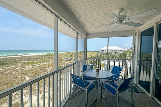 sunroom / solarium with ceiling fan and a water view