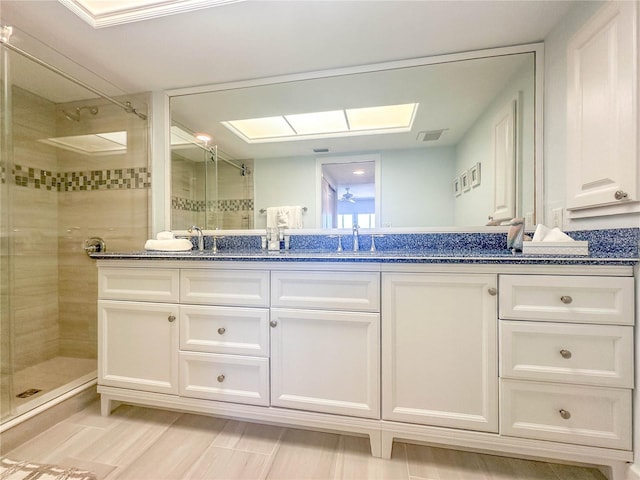 bathroom with tiled shower, a skylight, and dual bowl vanity