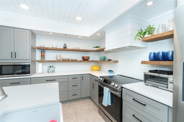 kitchen with appliances with stainless steel finishes, light tile floors, backsplash, gray cabinets, and wood ceiling