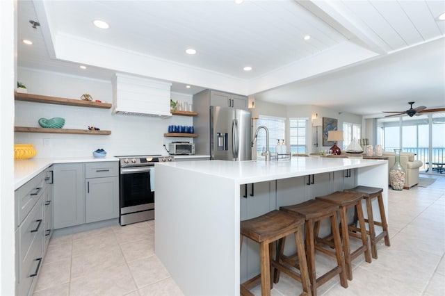 kitchen with stainless steel fridge, gray cabinetry, custom range hood, and a wealth of natural light