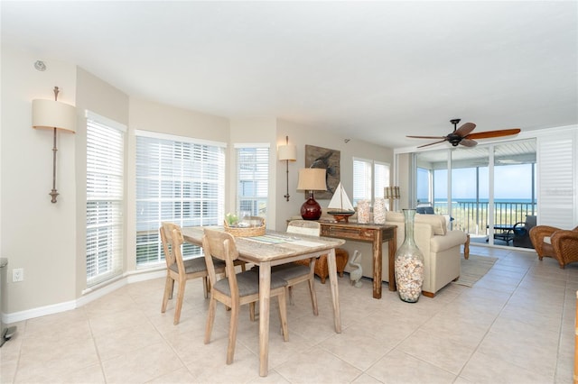 tiled dining space with ceiling fan and a water view