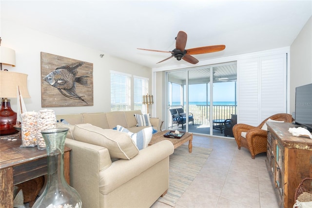 tiled living room featuring ceiling fan and a water view