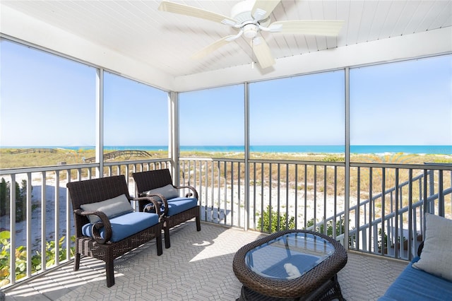 sunroom with ceiling fan and a water view