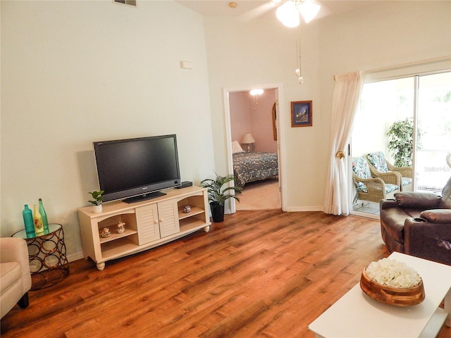 living room with a high ceiling, ceiling fan, and hardwood / wood-style floors