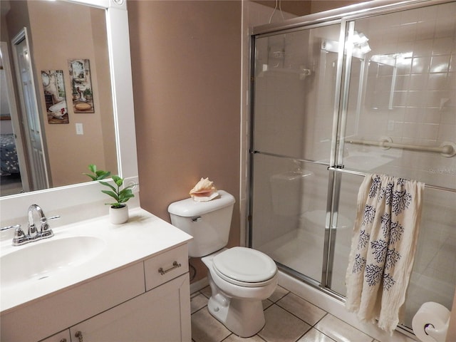 bathroom with tile patterned flooring, a shower with shower door, toilet, and vanity