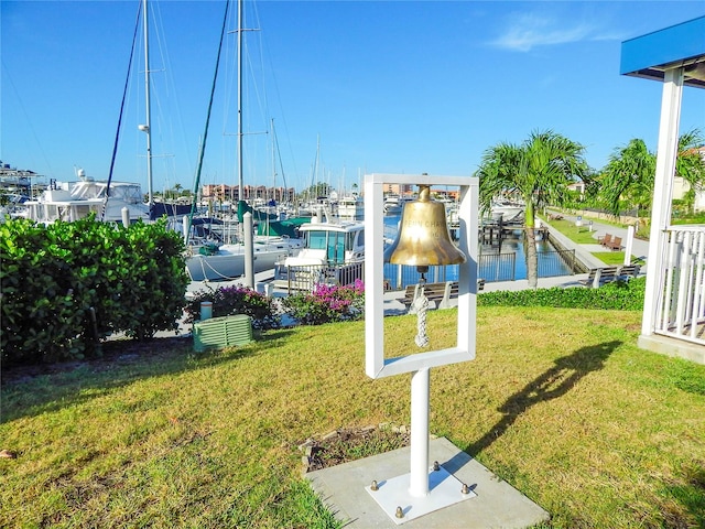 view of property's community featuring a yard, a water view, and a boat dock