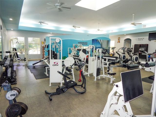 exercise room featuring a tray ceiling and ceiling fan