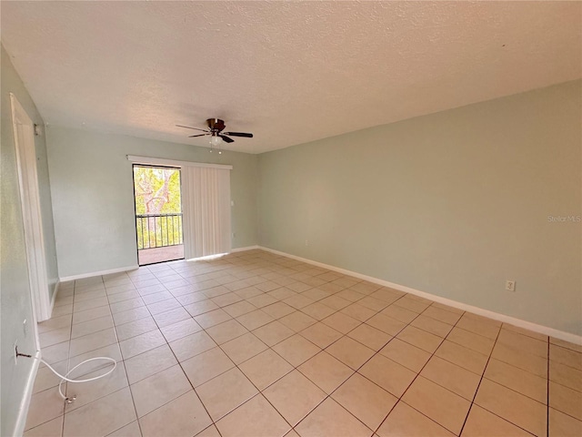 empty room with ceiling fan, light tile patterned floors, and a textured ceiling