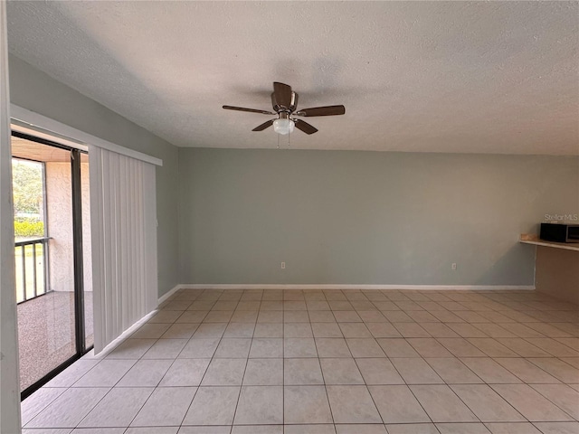 spare room featuring ceiling fan, a textured ceiling, and light tile patterned floors