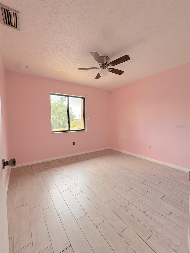 unfurnished room with ceiling fan and a textured ceiling