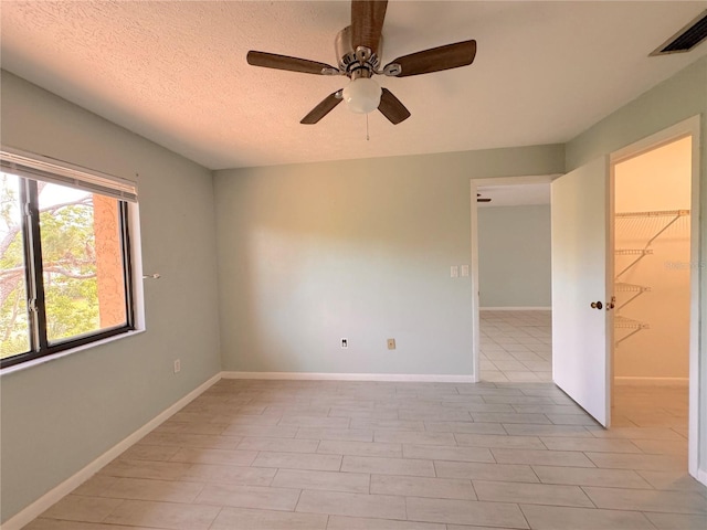 tiled spare room with a textured ceiling and ceiling fan