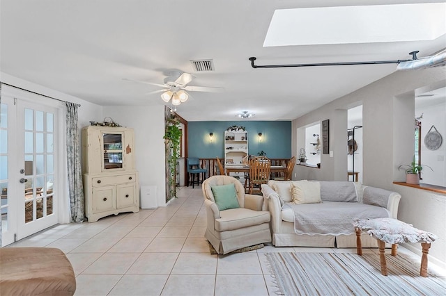 living room with ceiling fan, french doors, a skylight, and light tile floors