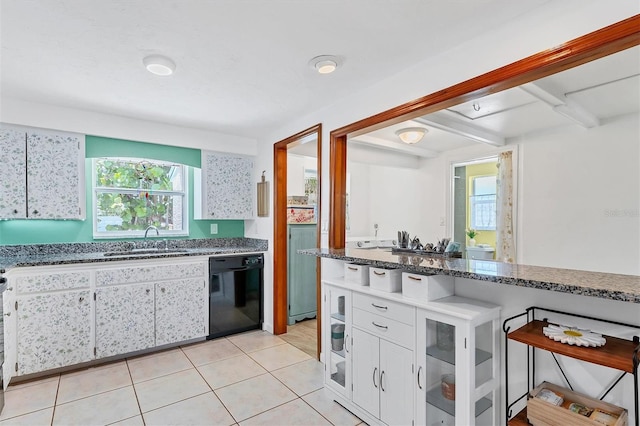 kitchen featuring light tile flooring, dark stone countertops, black dishwasher, sink, and white cabinetry