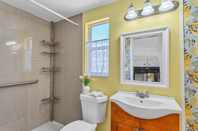 bathroom with a tile shower, vanity, and toilet