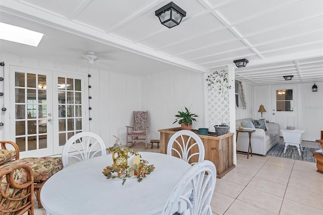 tiled dining space with ceiling fan, french doors, and a skylight