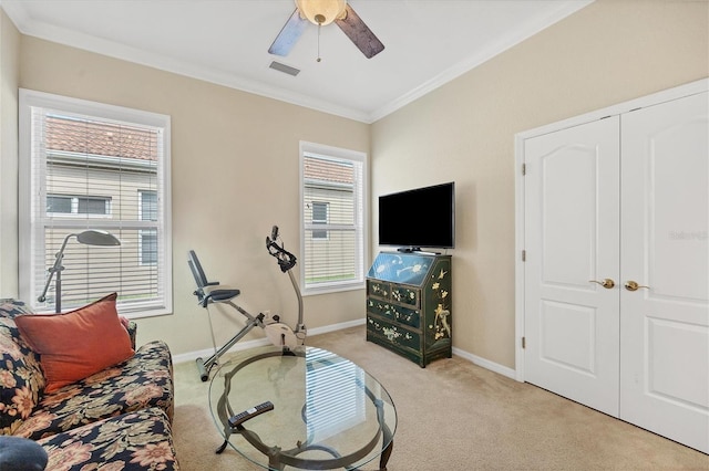 exercise room with crown molding, ceiling fan, and light colored carpet