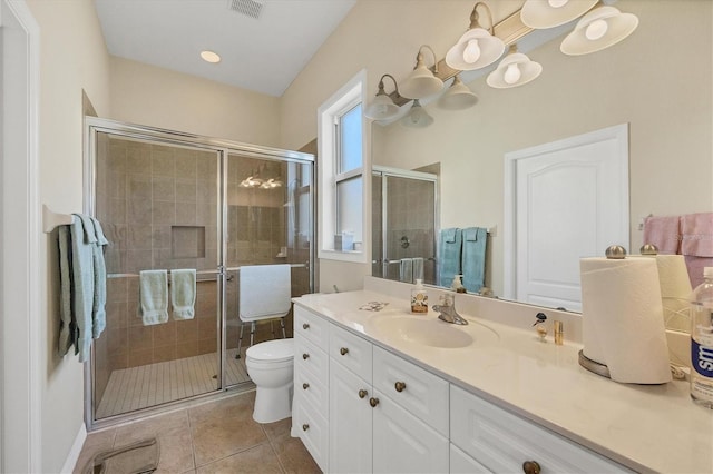 bathroom with tile patterned flooring, vanity, a shower with shower door, and toilet