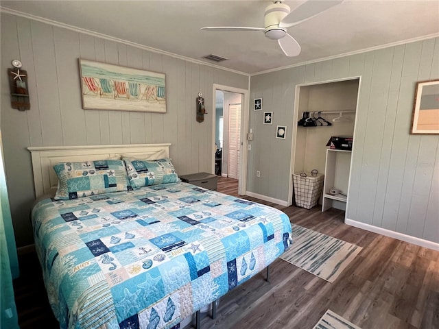 bedroom featuring ceiling fan, a closet, crown molding, and dark wood-type flooring