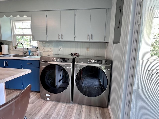 washroom with cabinets, sink, washing machine and dryer, and light wood-type flooring